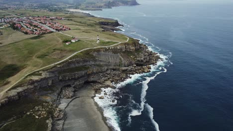 Ajo-lighthouse-on-cliffs-with-the-town-in-the-background,-Cantabria