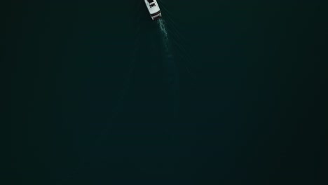 Drone-top-down-pan-across-yacht-tour-on-calm-dark-waters