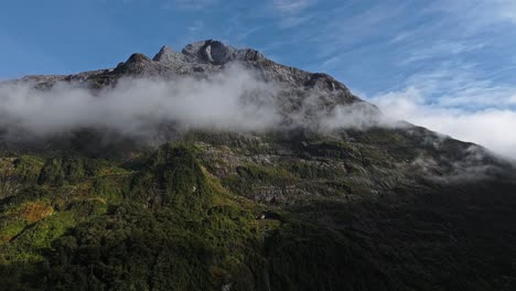 Grey-cloud-band-wraps-around-as-barren-peak-exposes-against-blue-sky