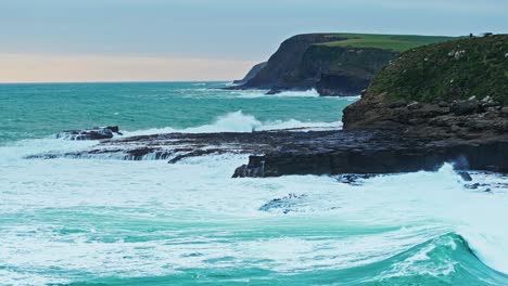 Waves-crash-and-build-powerful-sprays-along-rocky-shoreline-under-overcast-sky