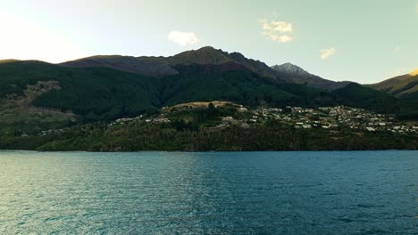 Aerial-frontal-dolly-establishes-Queenstown-New-Zealand-in-shadow-of-mountains
