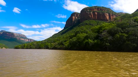 Brown-water-in-Blyde-river-canyon,-majestic-mountains-with-forest,-South-Africa
