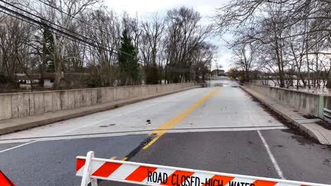 Road-closed---high-water-sign-at-bridge-with-flooding