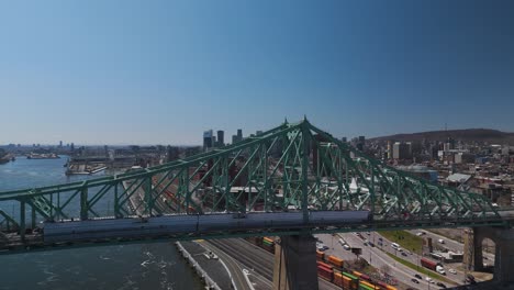 The-Jacques-Cartier-Bridge-in-Montreal-Island,-Montreal,-Quebec,-Canada-aerial-footage-with-car-crossing-Saint-Lawrence-River-leaving-behind-the-cityscape-of-the-city