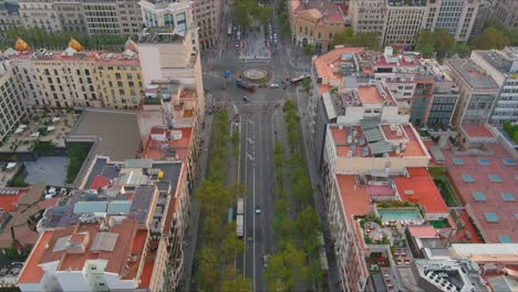 Barcelona-streets-flanked-by-buildings,-with-lush-trees,-early-evening-light,-aerial-view