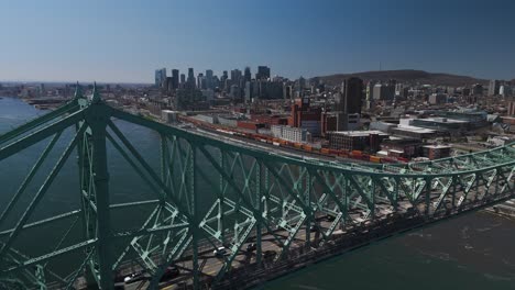 Drohnen-Nahaufnahme-Der-Jacques-Cartier-Brücke,-Die-Das-Stadtbild-Von-Montreal-Aus-Der-Ferne-Zeigt,-Aus-Der-Luft-Die-Skyline