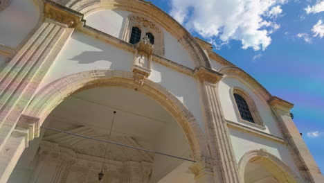 Die-Komplizierte-Fassade-Einer-Kirche-In-Lefkara-Mit-Klassischen-Architektonischen-Elementen-Und-Einem-Gewölbten-Eingang,-In-Sonnenlicht-Getaucht-Vor-Einem-Blauen-Himmel