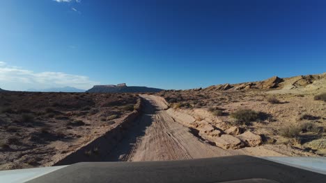 Drone's-eye-view-capturing-a-man-off-roading-a-sandy-road-from-a-front-view-perspective-embarks-under-bright-sun-soaked-journey-along-the-road-trails