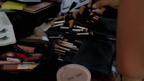 Slow-motion-shot-of-a-makeup-artist-selecting-from-a-large-collection-of-brushes