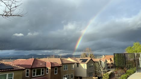 Rainbow-in-a-gray-sky-full-of-rain-clouds-appears-over-neighborhood-after-storm