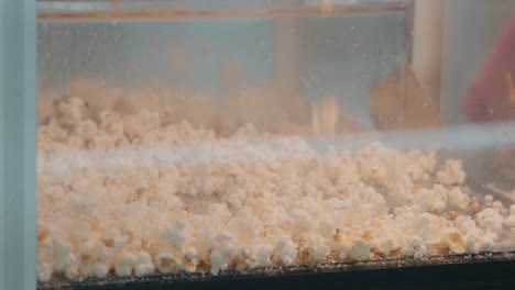 Golden-popcorn-tumbling-into-a-heated-glass-cabinet-at-a-fair