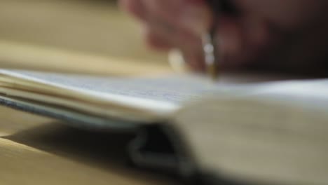 Closeup-long-static-shot,-writing-hands-place-ballpoint-pen-in-sketch-notebook