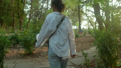 Woman-in-a-white-shirt-walking-through-a-lush-garden