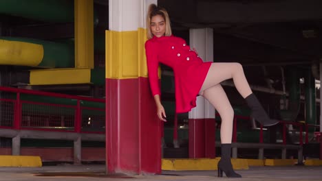 In-the-urban-parking-structure,-a-young-girl-of-Hispanic-descent-is-adorned-in-a-short-red-dress