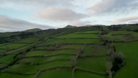 Rotierende-Luftaufnahme-Von-Kaskadierenden-Landschaften-Auf-Den-Azoren,-Portugal,-Die-Landwirtschaftliche-Tätigkeiten-Darstellen