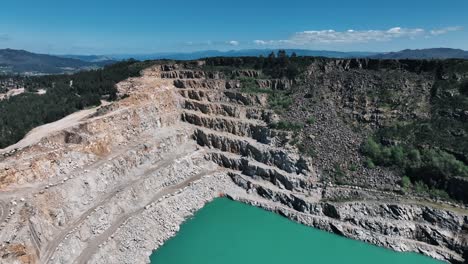 Amplia-Toma-Aérea-De-Un-Paisaje-De-Cantera-Escalonada-Con-Un-Lago-Turquesa.