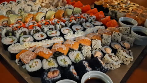 Variedad-De-Coloridos-Sushi-En-La-Mesa,-Acompañados-Con-Salsa-De-Soja.