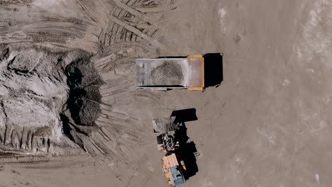 aerial-Overhead-shot-of-an-excavator-loading-sand-into-a-haul-truck