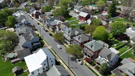Aerial-tracking-shot-of-white-car-on-road-in-quaint-american-Housing-area-at-sunlight