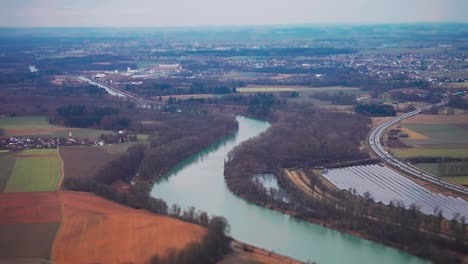 Eine-Luftaufnahme-Des-Flickenteppichs-Aus-Feldern,-Kleinstädten,-Wäldern-Und-Einem-Solarpark-Am-Flussufer-Im-Ländlichen-Deutschland