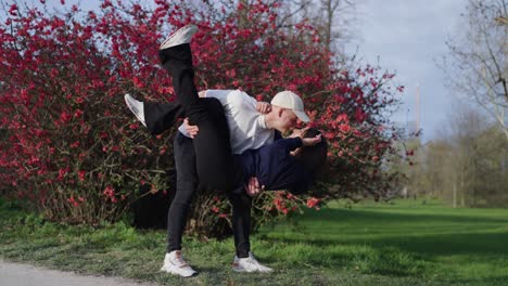 Guy-hold-girlfriend-in-bridal-style-and-kiss-near-blooming-Chinese-quince