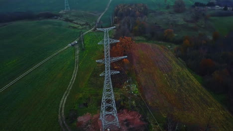Aerial-View-of-New-Electric-Pylon-Tower-in-Green-Countryside-Landscape-on-Dark-Autumn-Day
