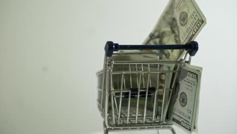 shopping-cart-loaded-with-usd-100-bills-spinning-on-white-background