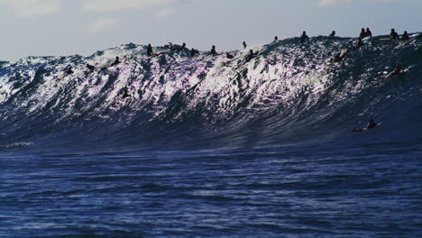Slow-motion-view-of-crowded-big-wave-surf-break-with-professionals-in-water