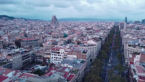 Barcelona-with-a-cloudy-sky,-showcasing-city-streets-and-distant-landmarks,-aerial-view