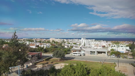 Vista-Panorámica-De-Protaras,-Que-Muestra-Una-Variedad-De-Edificios-Y-Vegetación-Que-Conducen-A-Las-Aguas-Azules-Del-Mar,-Bajo-Un-Cielo-Salpicado-De-Nubes.