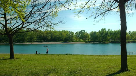 Sonniger-Tag-Am-Jarun-See,-Zagreb,-Mit-Menschen,-Die-Eine-Gemütliche-Rudertour-Und-Einen-Spaziergang-Am-Ufer-Genießen