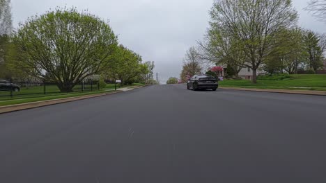 Black-vehicle-on-road-in-pretty-american-residential-area-in-spring-season