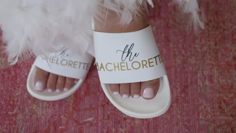 Bride-in-wedding-dress-wearing-comfortable-white-flip-flops-from-her-bachelorette,-painted-nails-close-up-shot