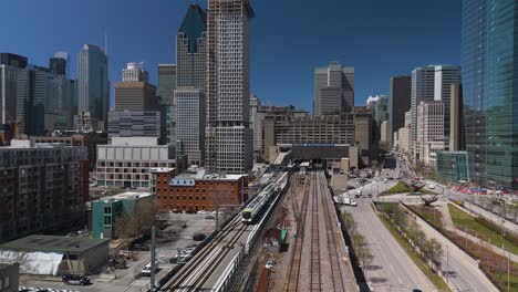 Aerial-of-REM-automated-light-rail-system-subway-train-entering-Montreal-city-with-skyline-building-in-Quebec-capital-,-Canada