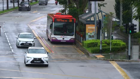 El-Tráfico-Diario-En-La-Calle-Y-El-Autobús-Salen-De-La-Parada-De-Autobús-En-El-Centro-De-Singapur-En-Un-Día-Lluvioso