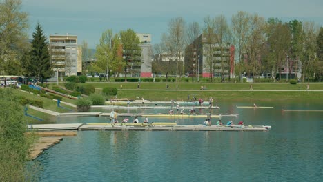 Rowers-training-on-the-calm-waters-of-Jarun-Lake-with-onlookers-and-cityscape-in-the-backdrop,-Zagreb,-Croatia