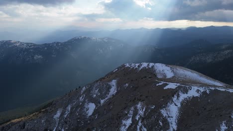 Ein-Großer-Lichtstrahl-Bricht-Zwischen-Den-Wolken,-Die-Im-Winter-Auf-Die-Berge-Des-Peloponnes-Herabfallen