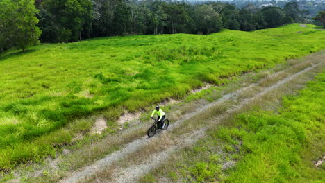 Aerial-rising-shot-of-mountain-biker-on-sportive-bicycle-riding-on-track-in-Mangrove-nature-of-Dominican-Republic