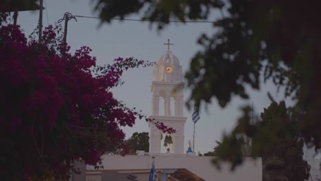 picturesque-view-of-the-Greek-flag-flying-in-Mykonos,-Greece-by-a-Greek-Orthodox-church-and-blue-dome-in-the-background