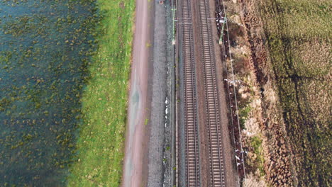 Parallel-Railway-Tracks-Next-to-E45-in-Gothenburg,-Natural-Surroundings,-Daytime,-Aerial-View