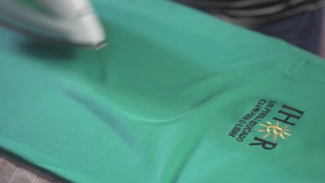 Close-up-of-young-Latin-woman's-hands-ironing-a-green-shirt