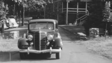 Vintage-Car-Drives-Down-a-Suburban-Street-in-the-Bright-Daylight-of-1930s-in-BW