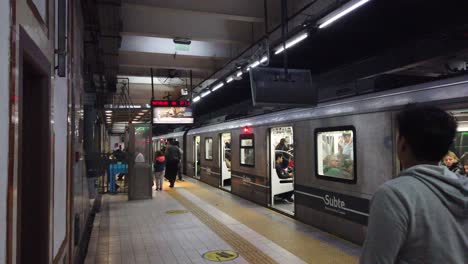 Menschen-Gehen-Vor-Der-U-Bahn-Von-Buenos-Aires-Spazieren,-Der-Zug-Wartet-Auf-Sitzende-Passagiere-An-Einem-Bahnhof-Im-Europäischen-Architekturstil