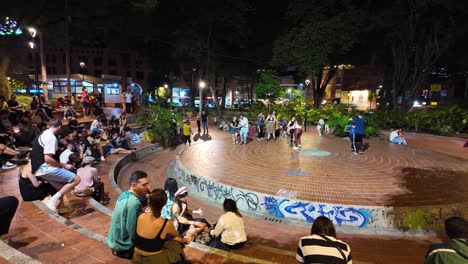 Animada-Escena-Nocturna-En-El-Poblado-De-Medellín,-Con-Lugareños-Disfrutando-De-Asientos-Al-Aire-Libre-Y-Una-Vibrante-Vida-Callejera.