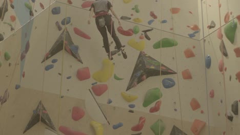 Climber-reaching-the-top-on-a-colorful-indoor-wall