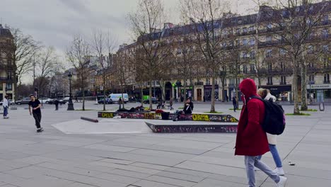 Skateboarders-practicing-tricks-at-Place-de-la-Republique-in-Paris,-overcast-day