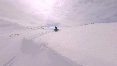 Aerial-FPV-View-Of-Snowmobile-Riding-Across-Snow-Covered-Slope-Near-Sharkstooth-Peak,-Colorado