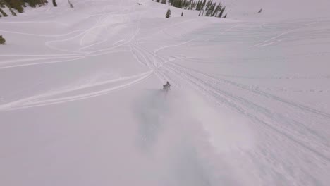 Snowmobile-Rider-Jumping-Off-Slope-With-Aerial-FPV-Following-Through-In-Sharkstooth-Peak,-Colorado