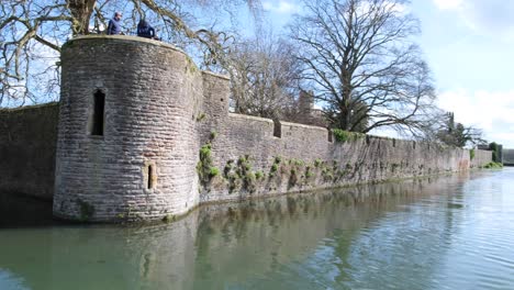 Scenic-pan-of-the-Bishop's-Palace-and-moat-on-a-sunny-day-in-the-city-of-Wells,-Somerset,-England