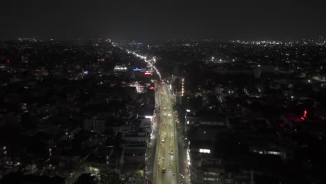 aerial-drone-shot-moving-towards-brightly-lit-apartments-skyscrapers-with-lights-and-highway